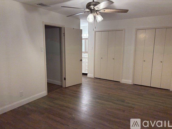 A room with a ceiling fan and wooden flooring.