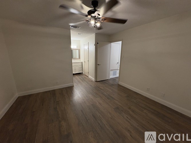 A room with a ceiling fan and wooden flooring.