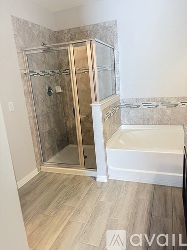 A bathroom with a glass shower door and a bathtub.