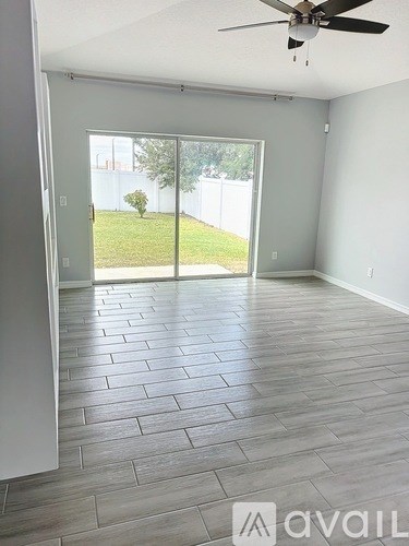 A room with a ceiling fan and sliding glass doors leading to a backyard.