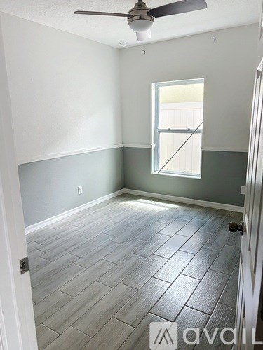 A room with a ceiling fan and a window with blinds.