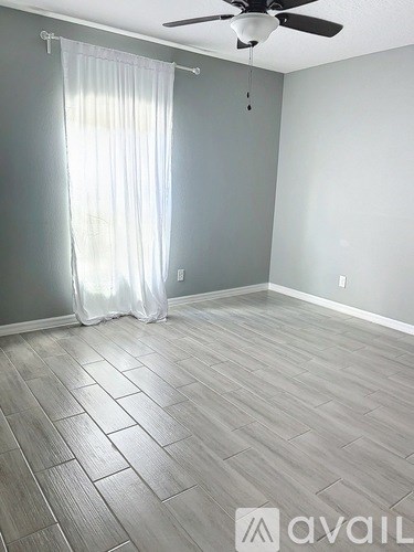 A room with a ceiling fan and a window with curtains.