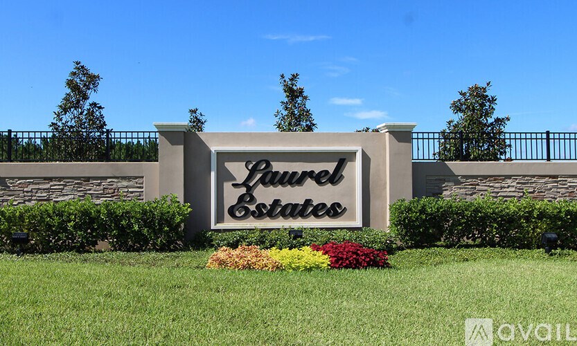 A sign that says Laurel Estates in front of a fence.
