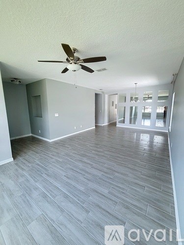 A room with a ceiling fan and wooden flooring.