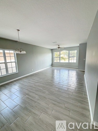 A spacious room with wooden flooring and a ceiling fan.