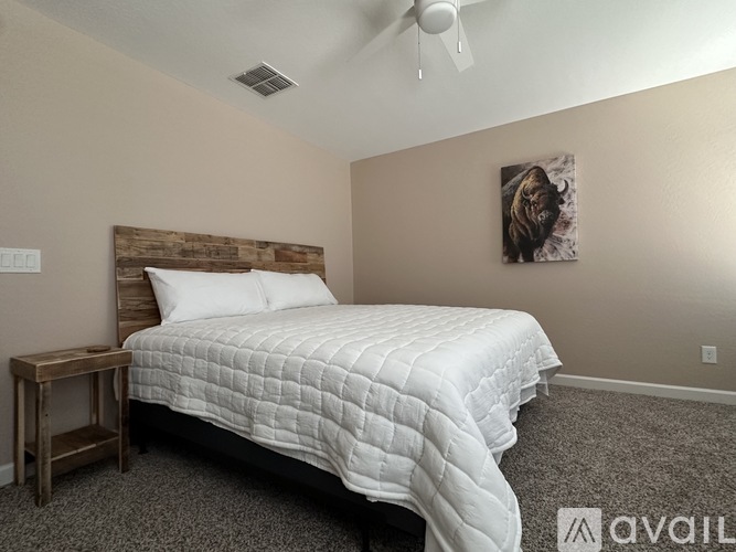 A bedroom with a bed, nightstand, and a painting on the wall.