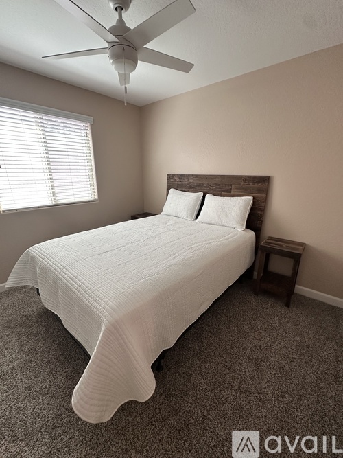 A bedroom with a bed, a ceiling fan, and a small table.
