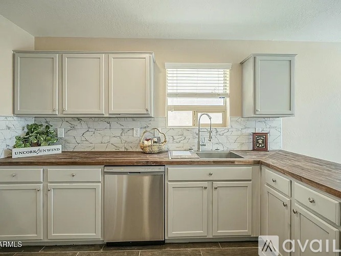 A kitchen with beige cabinets and a marble backsplash.
