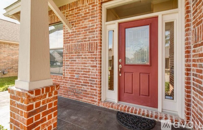 A red door is on the front of a brick house.
