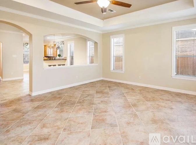 A spacious room with tiled flooring and a ceiling fan.