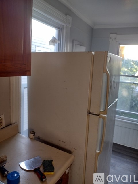 A white refrigerator in a kitchen with wooden cabinets.