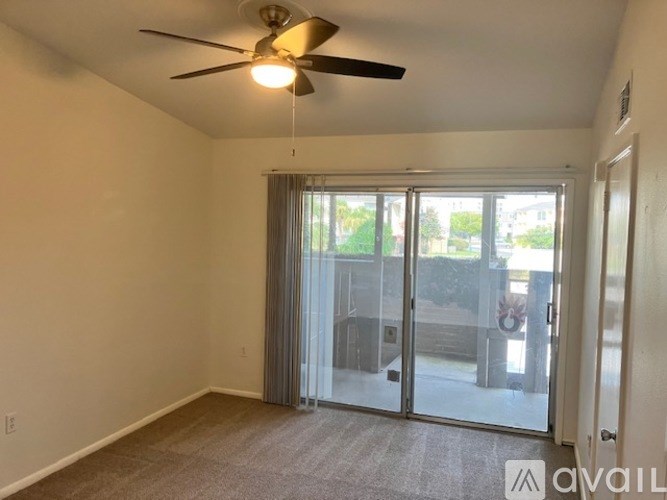 A room with a ceiling fan and sliding glass doors leading to a balcony.