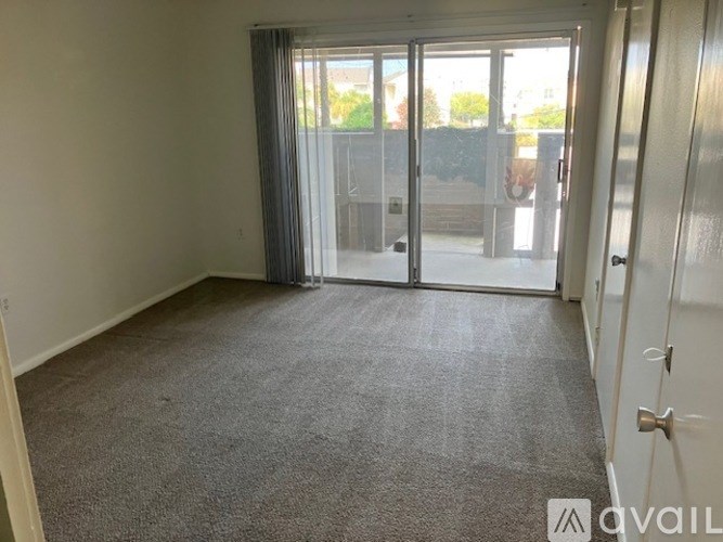 A carpeted room with a sliding glass door leading outside.