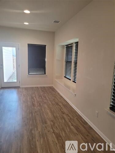 A room with wooden flooring and a window with blinds.
