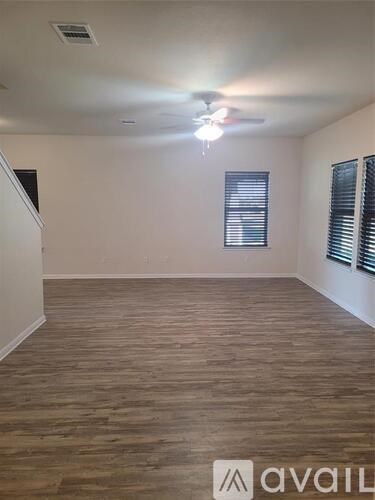 A room with wooden flooring and a window with blinds.