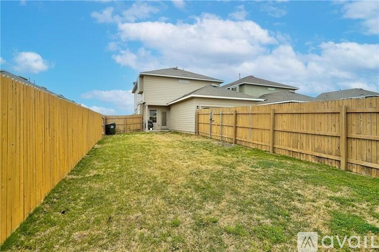 A backyard with a wooden fence and a house in the background.