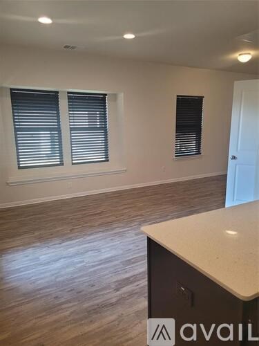 A room with a wooden floor and a counter with a window.