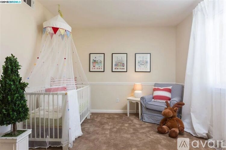 A baby's room with a crib, a teddy bear, a chair, and two pictures on the wall.