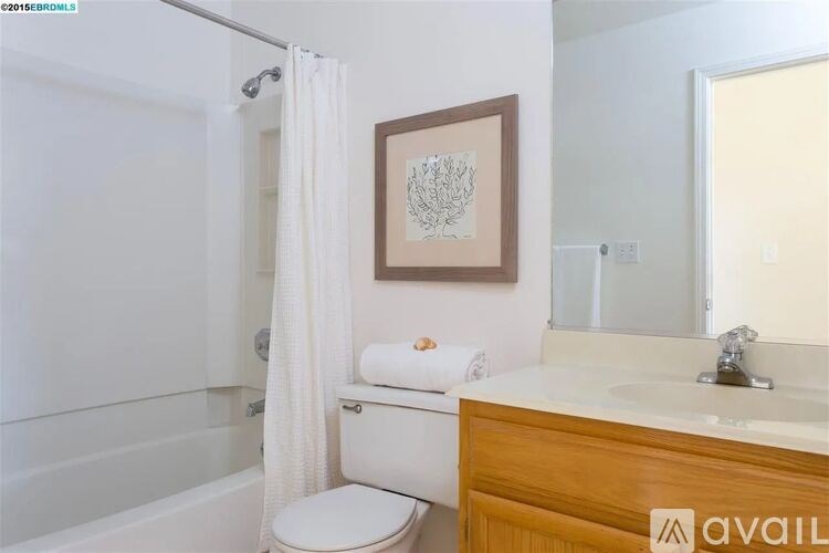 A bathroom with a toilet, sink, and a picture on the wall.