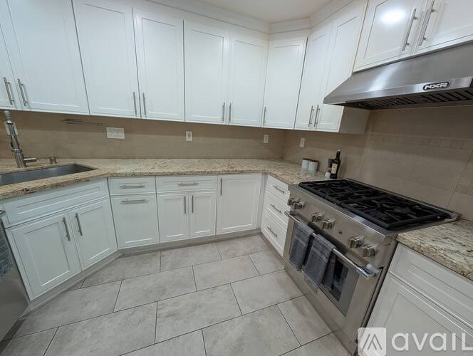 A kitchen with white cabinets and a stainless steel range hood.