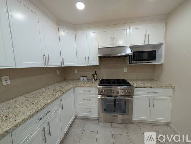 A kitchen with white cabinets and a granite countertop.