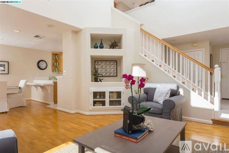 A living room with a grey couch, a wooden table, and a staircase.