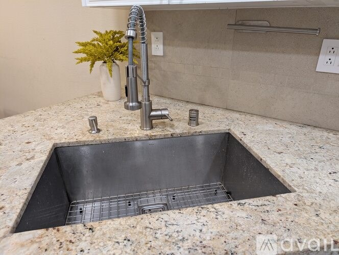 A kitchen sink with a silver faucet and a grey drain grid.