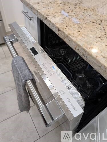 A silver oven with a grey towel hanging on it.