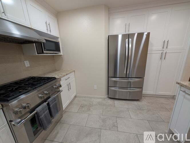A kitchen with a stainless steel refrigerator, microwave, and oven.