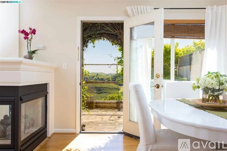 A white chair is in front of a table with a vase of flowers on it.