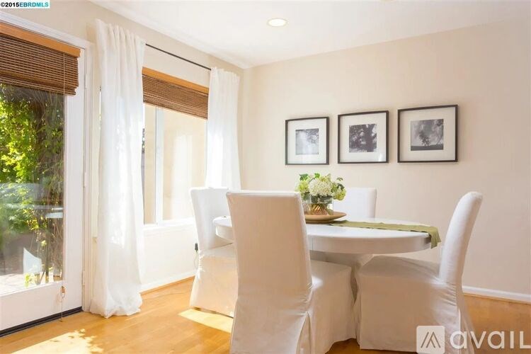 A dining room with white chairs and a table with a green placemat.