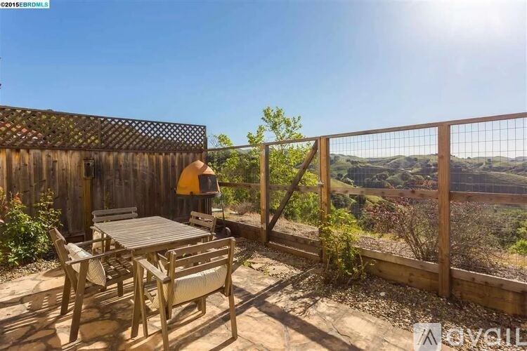 A patio with a table and chairs overlooking a valley.