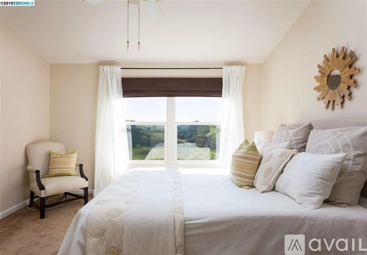 A bedroom with a large bed, a chair, and a window with a view of the outdoors.