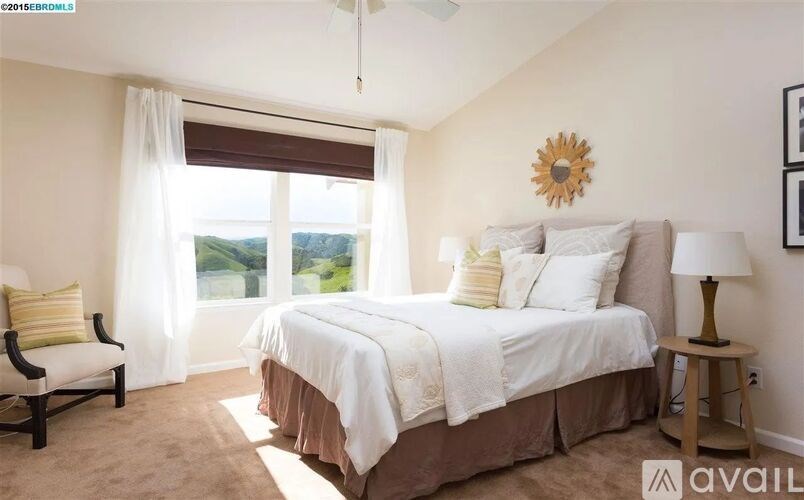 A bedroom with a large bed and a chair by the window.
