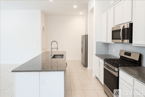 A kitchen with white cabinets and black countertops.