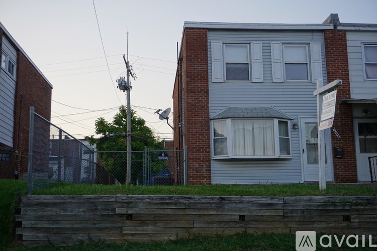 A house with a fence and a tree in front of it.
