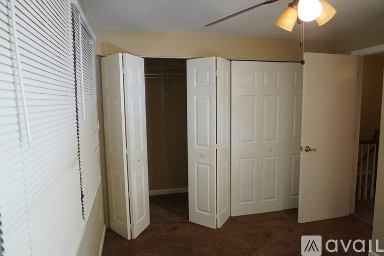 A room with a carpeted floor and a ceiling fan.