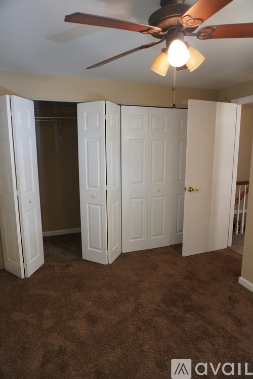 A room with a ceiling fan and carpeted floor.