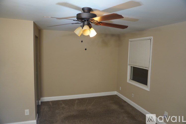 A room with a ceiling fan and carpeted floor.