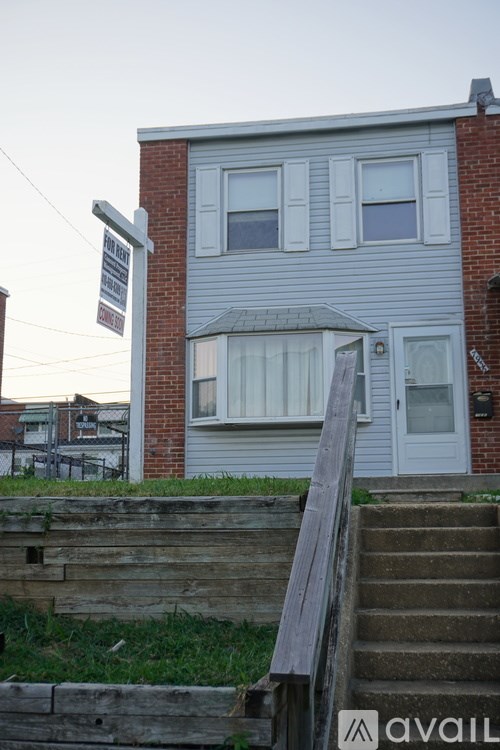 A house with a grey facade and a white door is for sale.