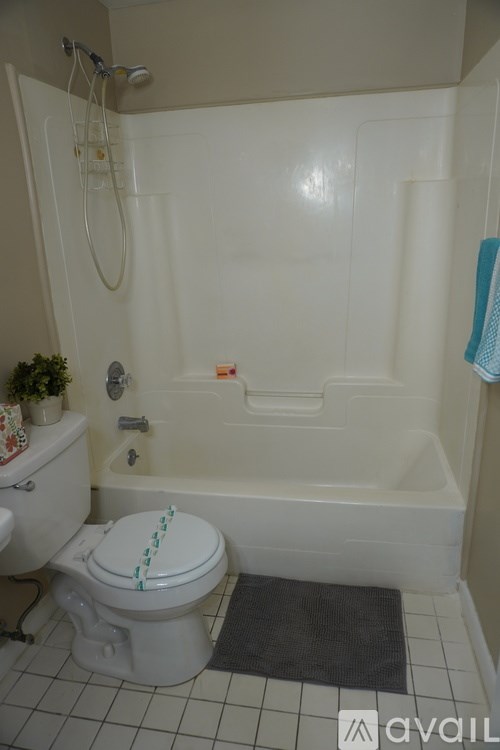 A white toilet with a blue towel on the side of a bathtub.
