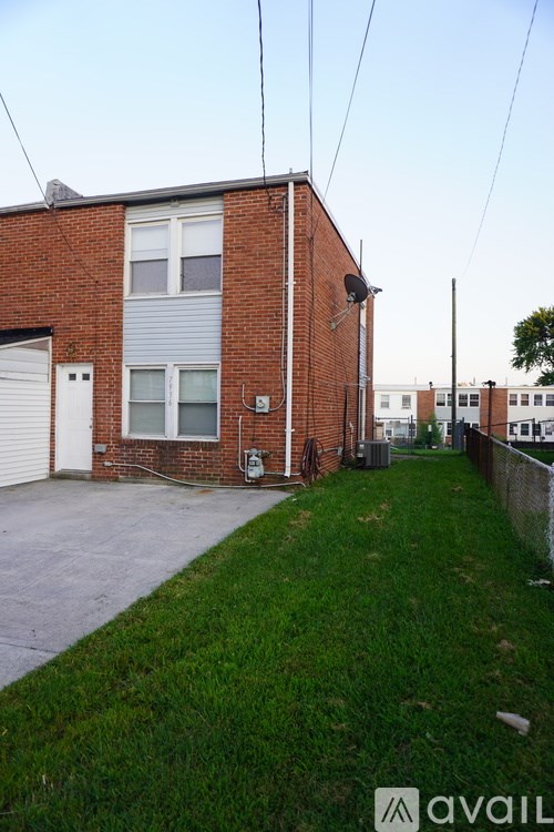 A red brick house with a white garage door and a green lawn.