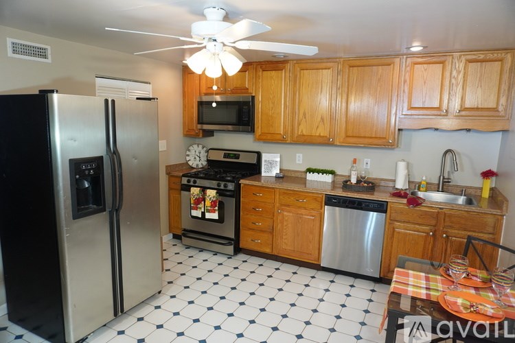 A kitchen with a black refrigerator and wooden cabinets.