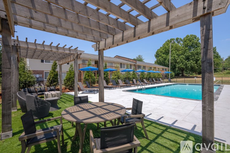 A wooden pergola over a table with chairs and a pool in the background.