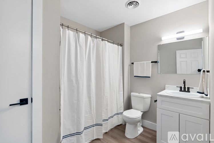 A white bathroom with a toilet, sink, and shower.