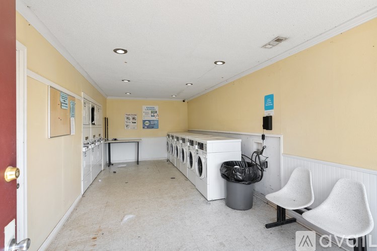 A room with a washing machine and a trash bin.