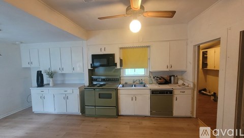 A kitchen with white cabinets and green appliances is available for rent.