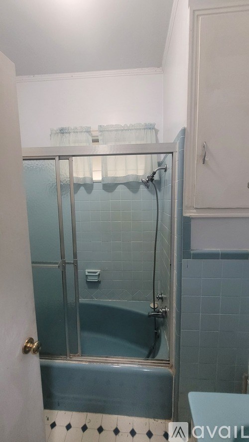A bathroom with a blue tiled shower and a white door.