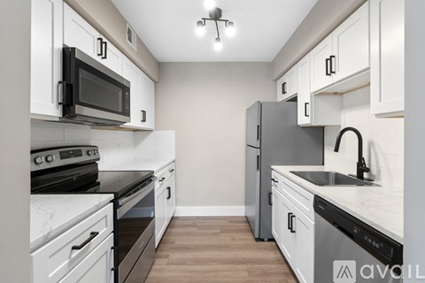 A kitchen with white cabinets and black appliances.