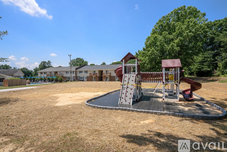 A playground with a slide and a wooden structure is in the foreground with apartment buildings in the background.